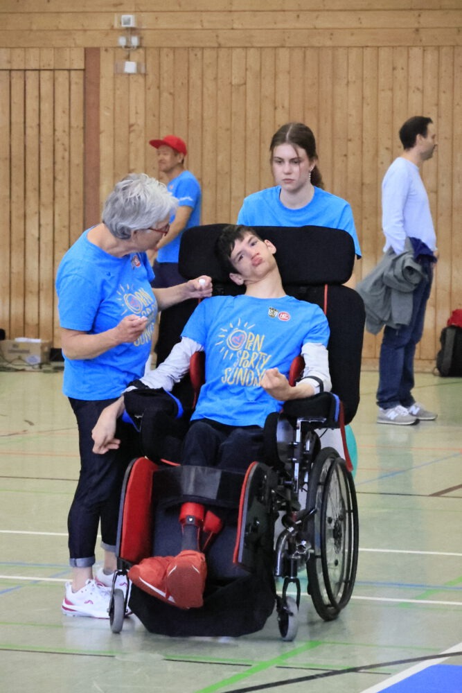 Teilnehmende beim inklusiven Sportangebot in der Halle, darunter ein junger Mann im Rollstuhl mit Betreuerinnen
