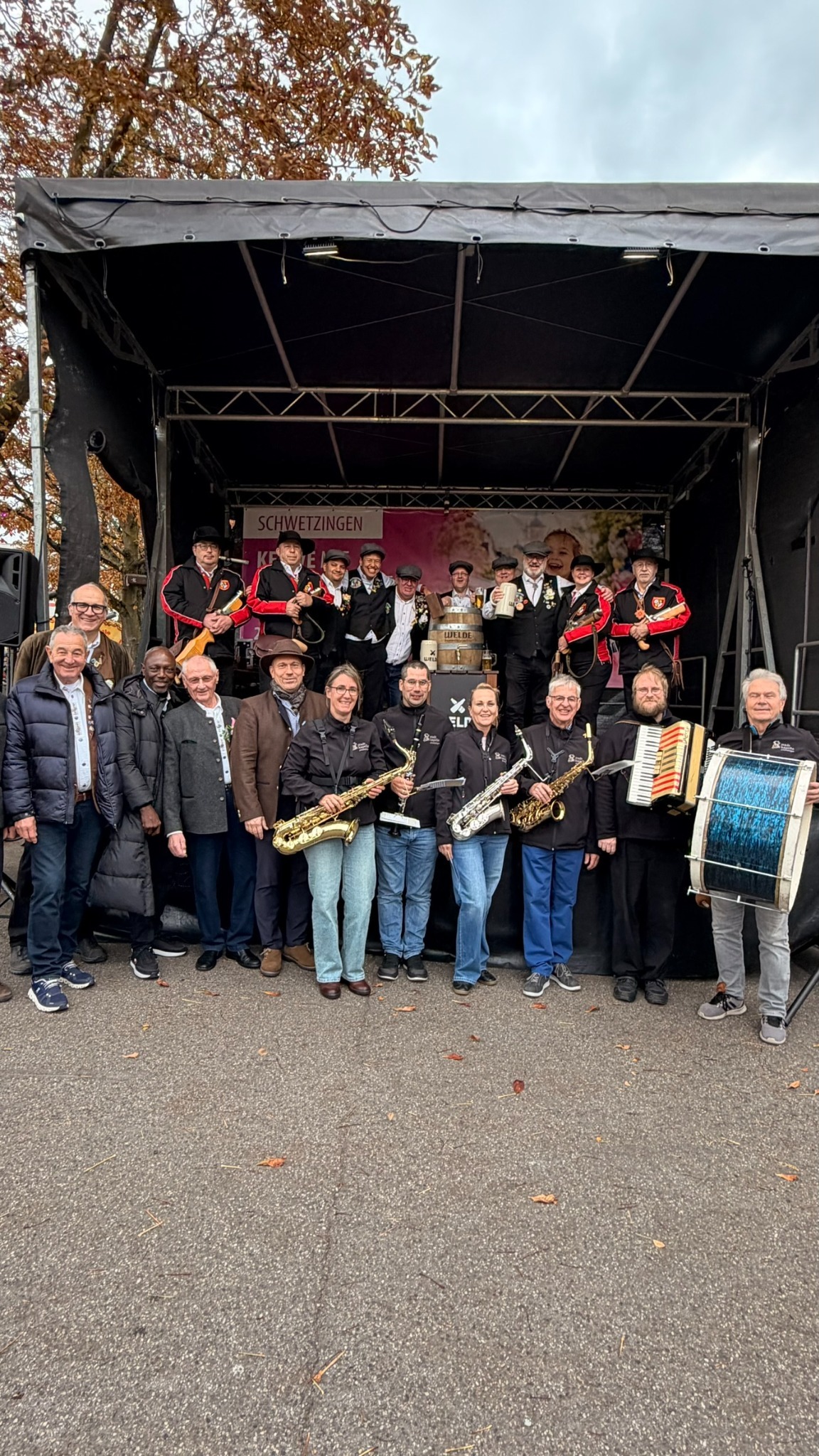 Gruppenfoto der Schwetzinger Kerweborscht und der Musikerinnen und Musiker vor der Festbühne.