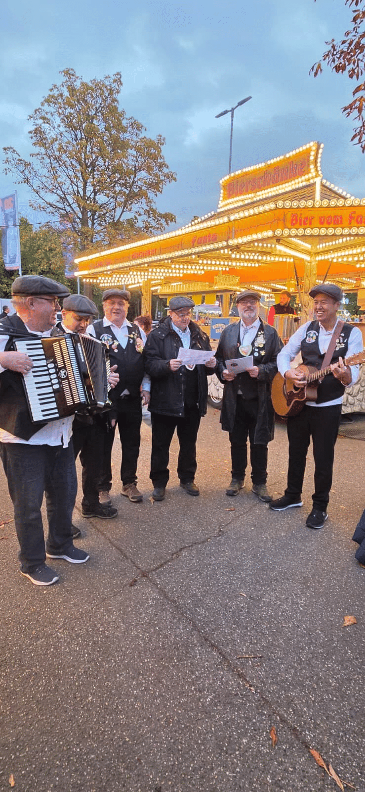 Kerweborscht singen vor einem beleuchteten Festzelt, begleitet von Akkordeon und Gitarre.